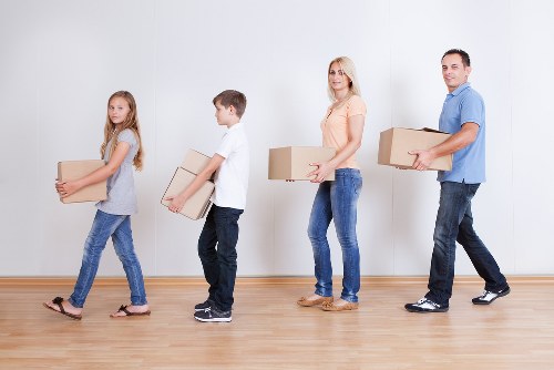 Professional movers carrying furniture through a London residential building